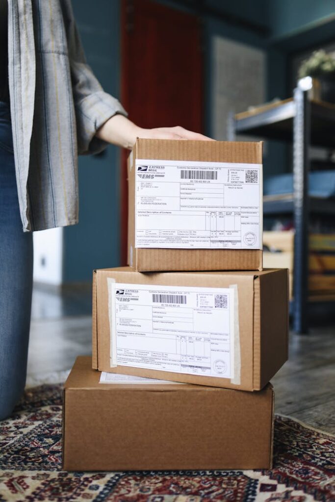 pexels-photo-4440800 A stack of brown cardboard boxes with shipping labels ready for mail delivery.